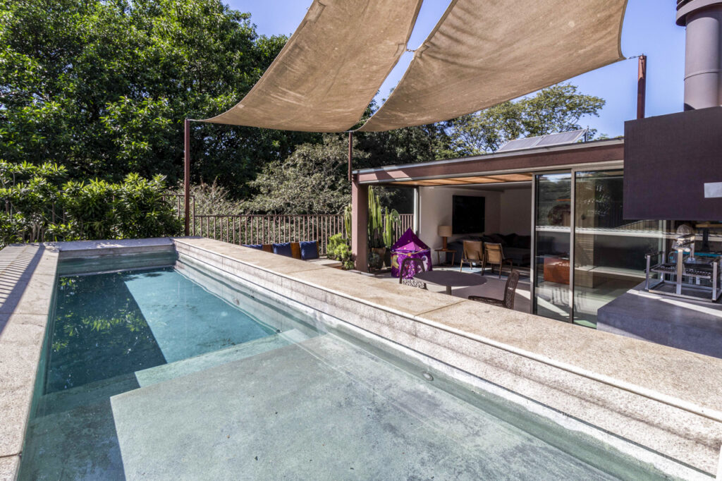 piscina com borda infinita em residência de luxo cercada por natureza em condomínio fechado